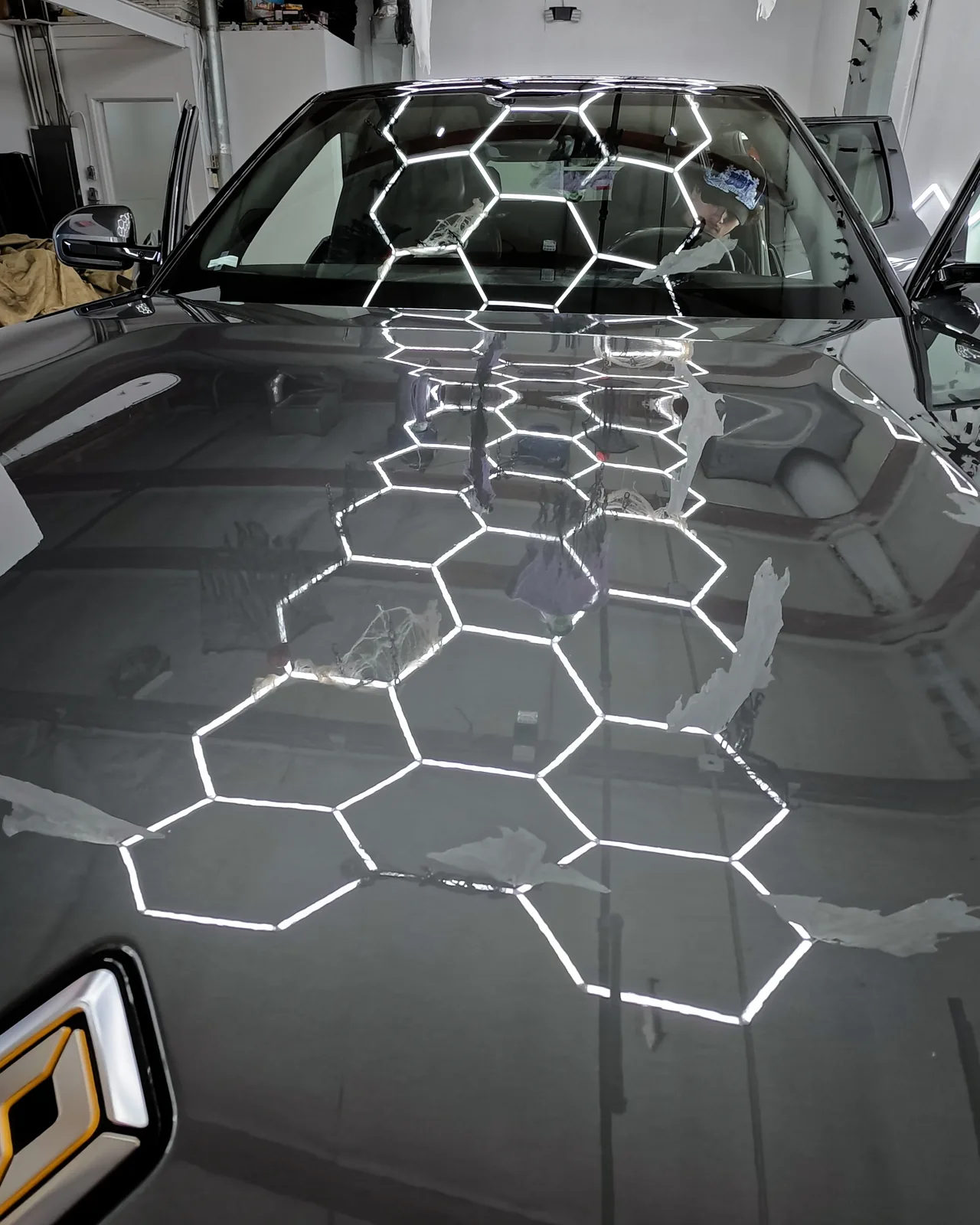 The Rivian R2 hood reflecting the shop ceiling lights — Oka's Car Care, Mountain View