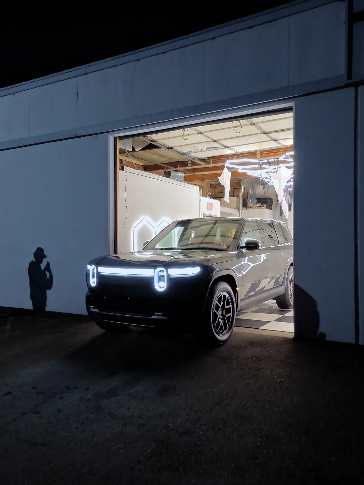 The finished Rivian R2 at the open bay door at night — Oka's Car Care, Mountain View